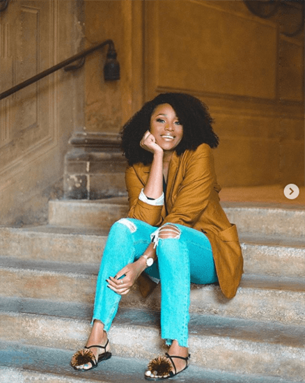Nigerian influncer Dimma Umeh sitting on steps in jeans and a blazer