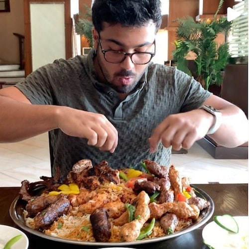 Abdul Rahman feasting on an Egyptian dish with rice, chicken kebabs, and vegetables