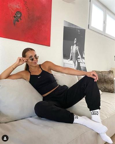 Model and Swiss influencer Mirjana Mira Zuber lounging on a couch in black joggers and a tank