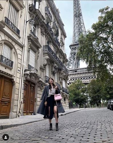 Luxury fashion influencer Mel in Melbourne walking a Paris street with the Eiffel Towerin the background and holding a Hermes bag