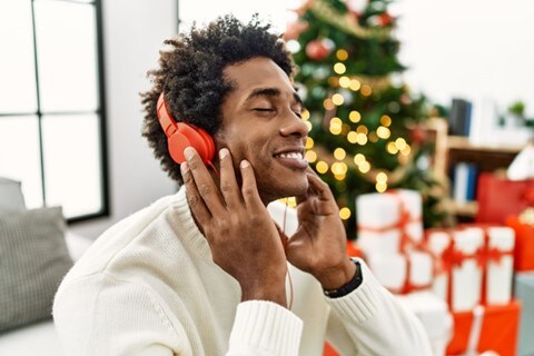 image of man dressed in white listening to music with red over the ear headphones