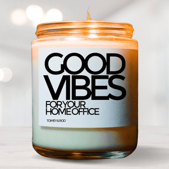 A jar of TomeyRod Home Office Good Vibes Work from Home Candle on top of a beige wooden table
