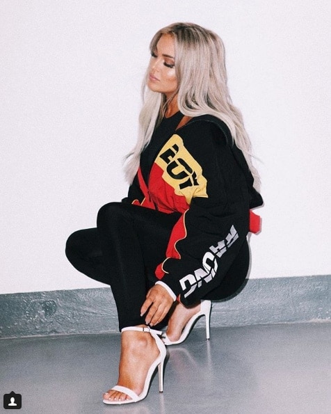 Influencer Fanny Lyckman squatting in cream heels in black outfit
