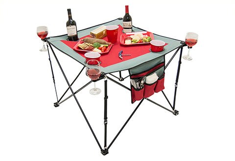 red foldable tailgate table with cupholders holding wine and food