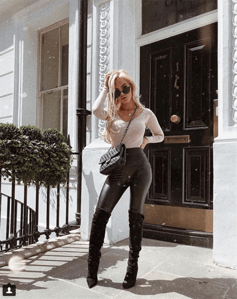 Influencer Sophie Elise wearing over the knee boots with black leather leggings in front of a black door