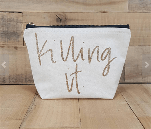 Cream colored zipped makeup bag with shimmery gold letters