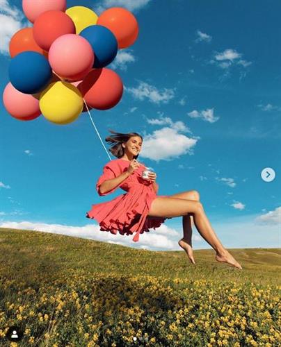 Canadian influencer Ania Boniecka flying above a field of flowers with balloons