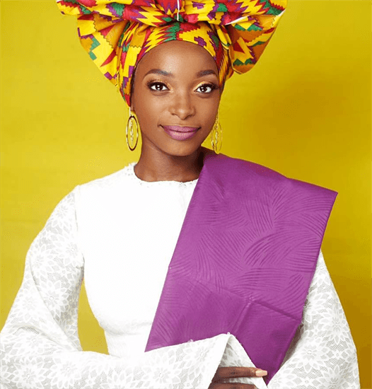 Mozambican influencer Witnei Shamusso wearing a traditional head wrap and white dress with Purple sash