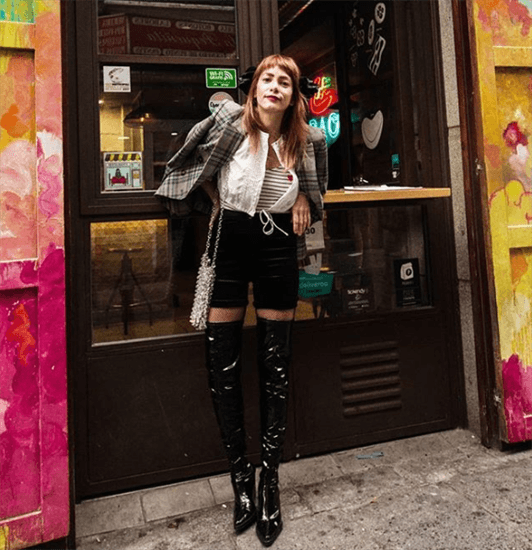 Influencer Valentina Rios wearing black shorts and over the knee black leather boots