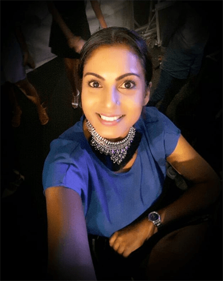Nalini Aubeeluck smiling in a blue top against a dark background