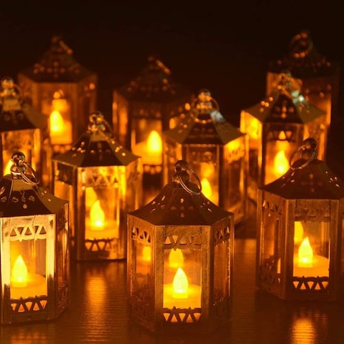 A Set of 8 Golden Brushed zkee Mini Star Lantern with Flickering LED inside a dark room
