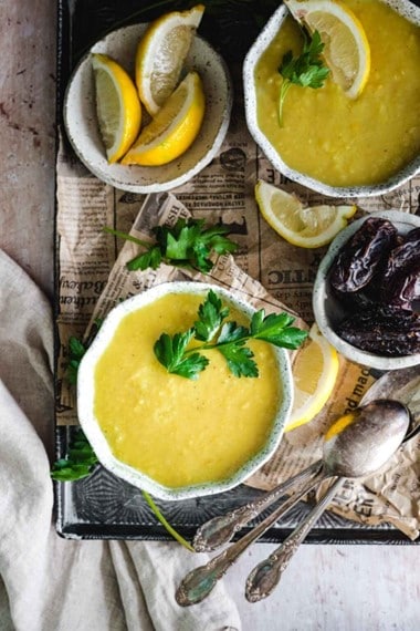 white bowls filled with lentil soup, dates, and lemons