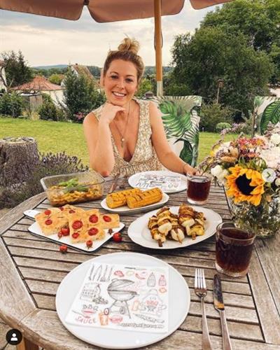 German influencer Ann-Christin Weber sitting at a picnic table surrounded by baked goods