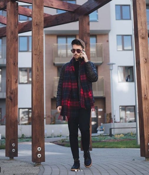 Influencer Darek Kozdras wearing black leather jacket and red plaid scarf with phone to his ear