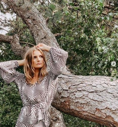 Danish influencer and blogger Cecilie Rubini posing in a striped dress near a large tree