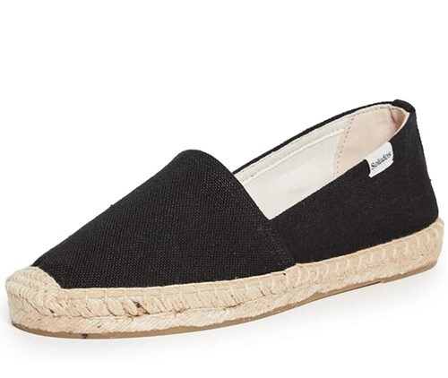  A single black espadrille by Soludos with tan rubber sole and a small simple brand logo on the side