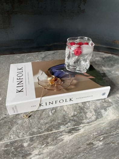 Kinfolk faux coffee table book on a table with a drink and jewelry on top