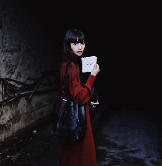 Influencer Emi Suzuki wearing long red coat under a dark tunnel