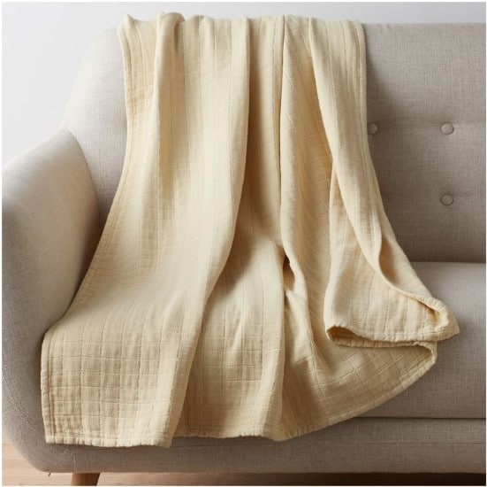 The Company Store Lightweight Gossamer cotton blanket in beige on a sofa
