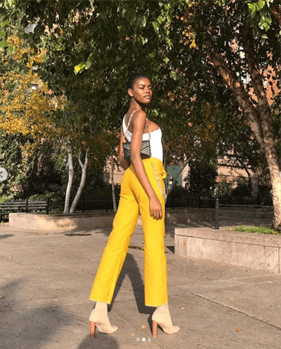 Influencer Amilna Estevao wearing bright yellow pants and heeled boots
