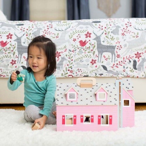 Toddler playing with the Fold & Go mini dollhouse in pink