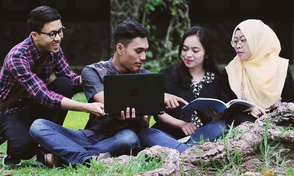 Four children sitting in grass studying