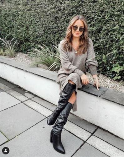 Irish model, nutritionist, and influencer Jodie Matthews sitting on a bench in a tan sweater dress and black boots