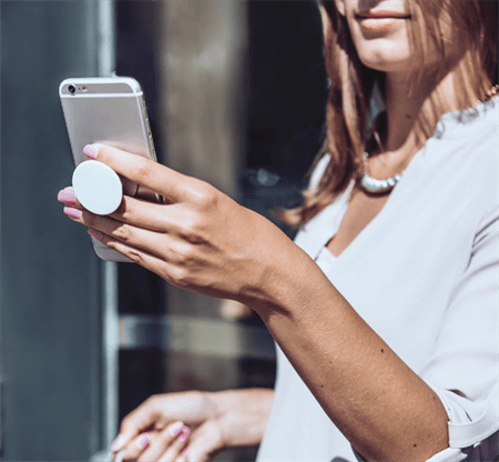 Woman holding cellphone with fingers in between popsocket