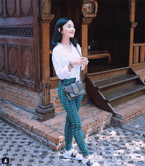 Influencer Nanda Arsyinta wearing teal plaid pants in front of historic building
