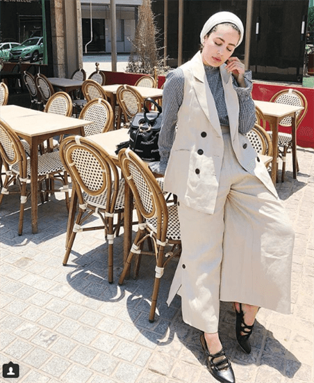 Blogger Ascia al Faraj sitting on table outside wearing beige hijab and beige outfit