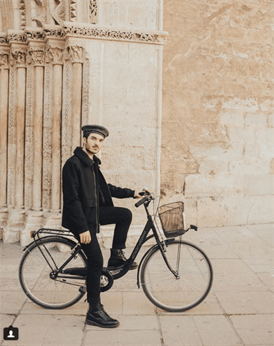 Influencer Tommaso sitting on bike in all black outfit