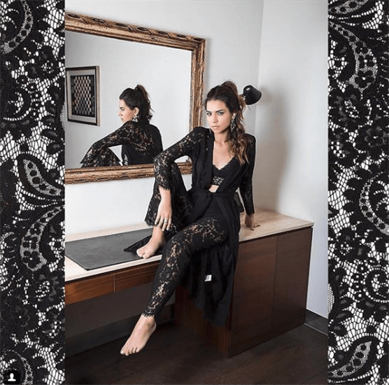 Influencer >Annie Catalan sitting on desk wearing black lace bodysuit