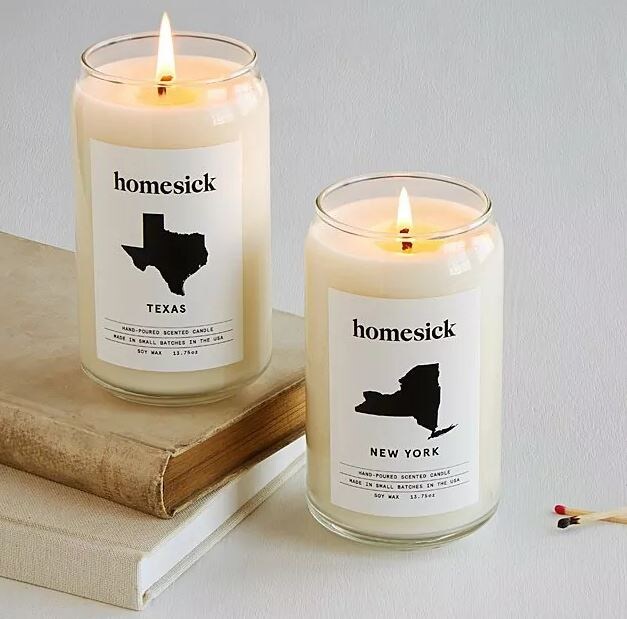 two home sick candles that show silhouette images of new york state and texas