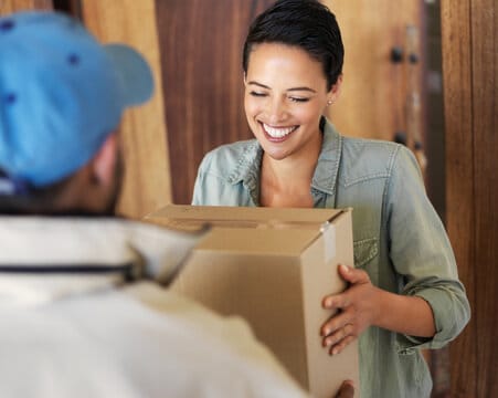 Smiling woman receiving a package from a postman