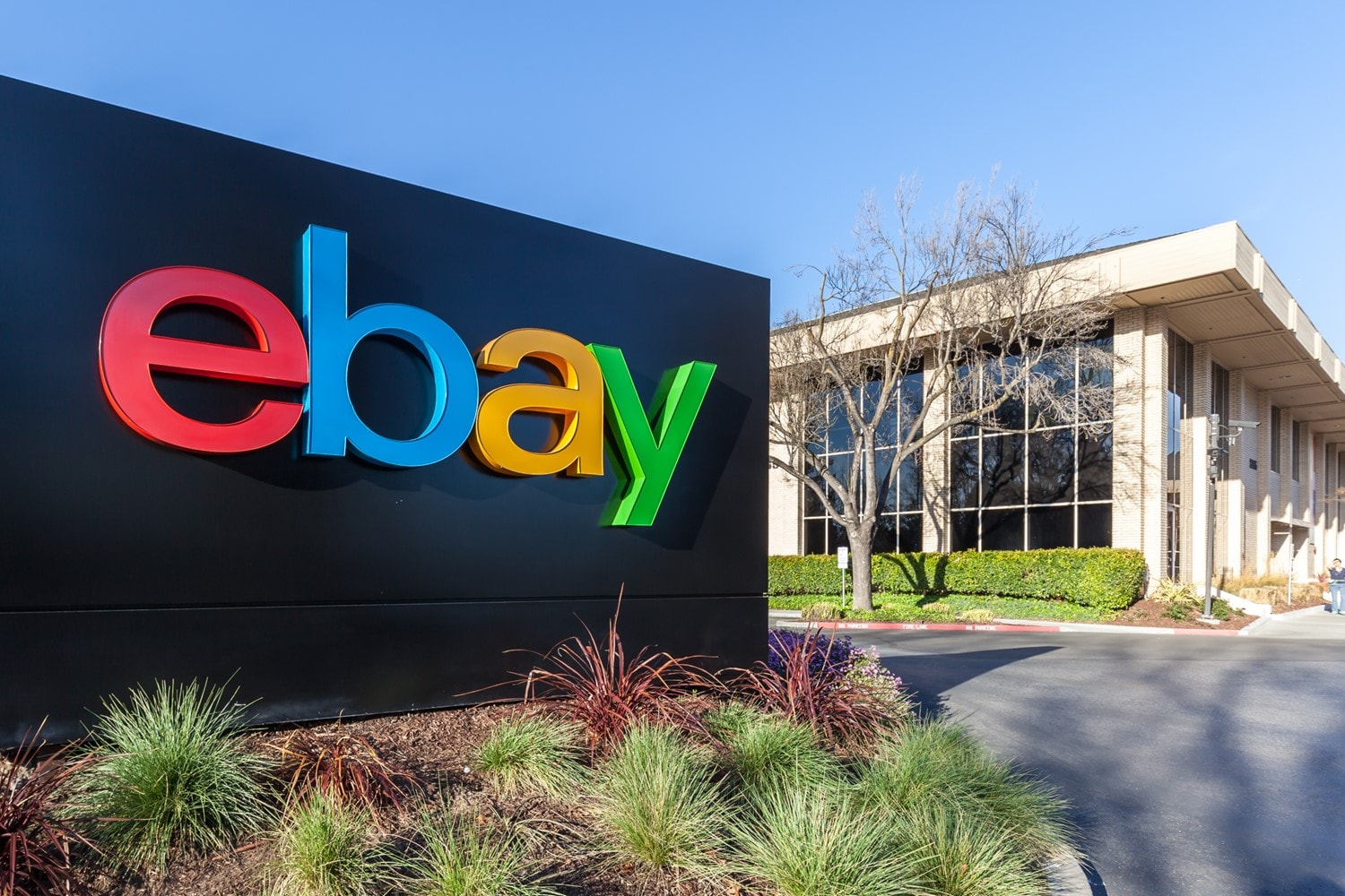 A black sign with the eBay logo sits in front of an office building.