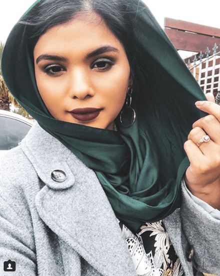 Influencer Aisha Baker wearing an emerald green silk hijab and gray pea coat