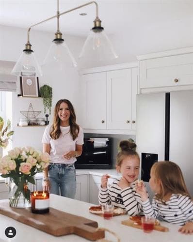 Irish blogger and influencer Anna smiling for the camera in her kitchen with her two daughters