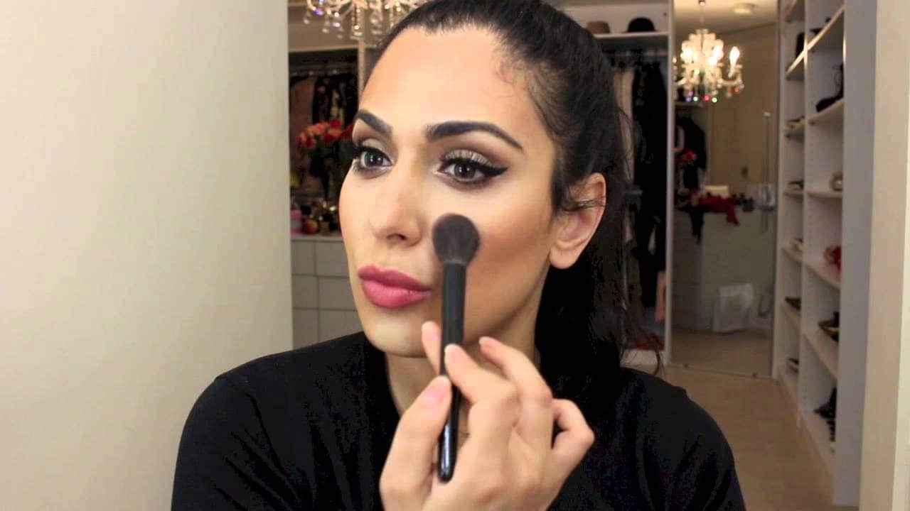 Huda Kattan brushing on makeup on her face