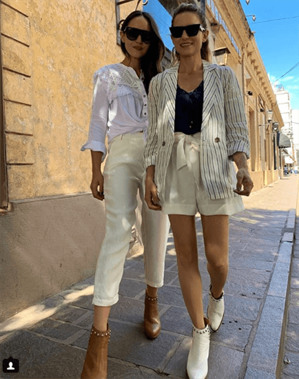 Bloggers Sabina Hernandez and Lucia Nini walking down brick sidewalk wearing sunglasses and studded boots