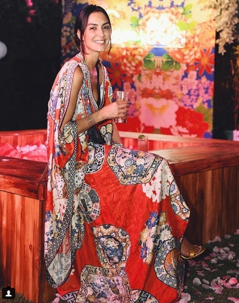 Blogger Jenny Lopez wearing patterned formal dress sitting on bench