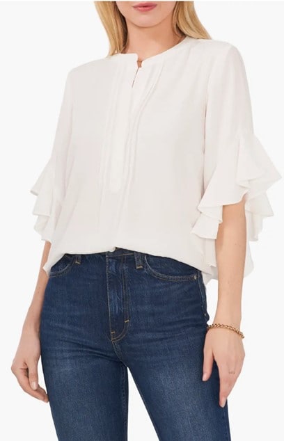 Woman wearing a ruffle sleeve split neck blouse paired with dark blue jeans