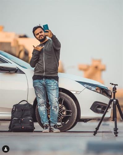 Pakistani social influencer Irfan Junejo taking a selfie in front of a white Infiniti XS5