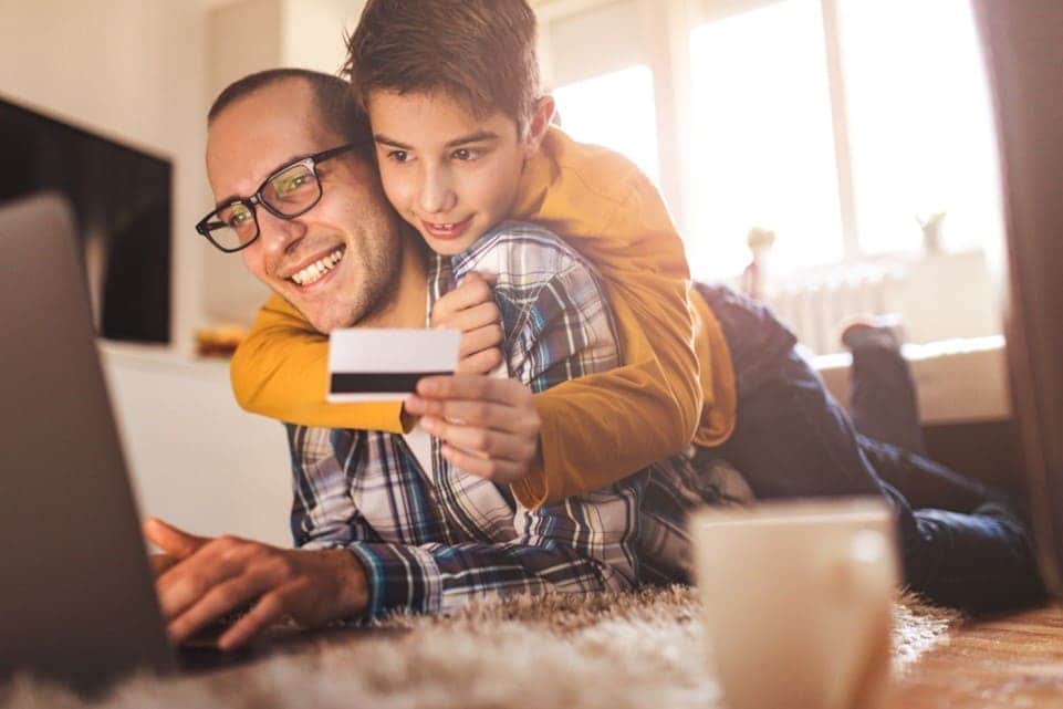Dad and son using a laptop to shop online at home