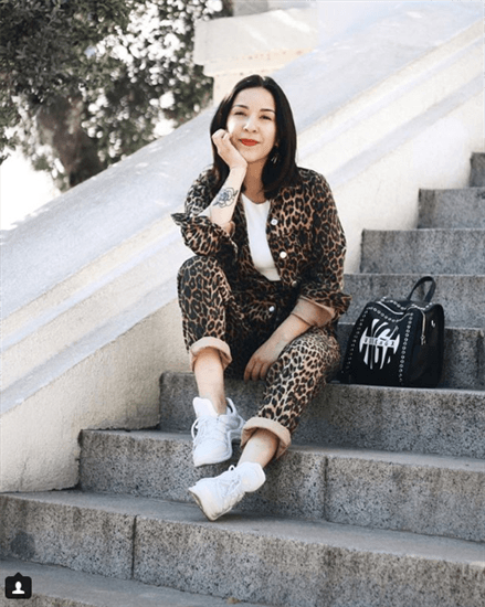 Influencer Vivi Valenzuela wearing cheetah print pants and jacket sitting on steps