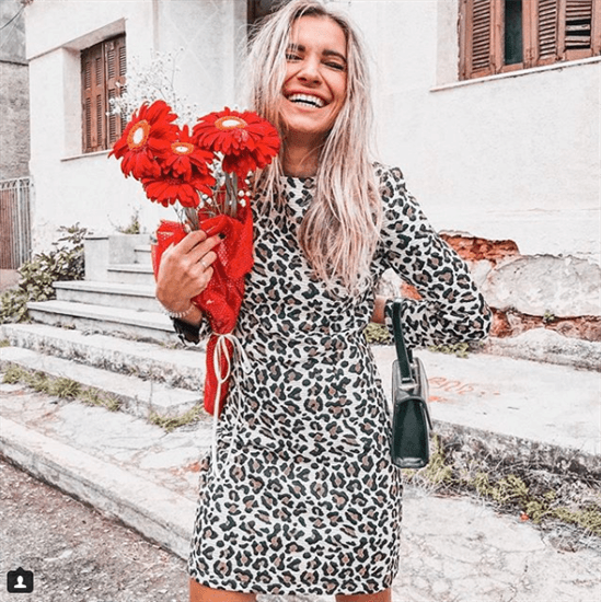 Fashion Blogger Oanna Popa wearing cheetah print dress holding red daisies