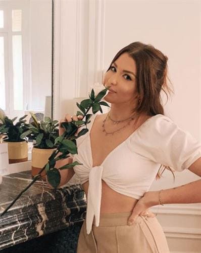 French influencer Marie Lopezin a white crop top smelling a white rose