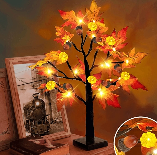 Turnmeon’s maple tree tabletop light placed on a nightstand next to a book and a framed photo of a train