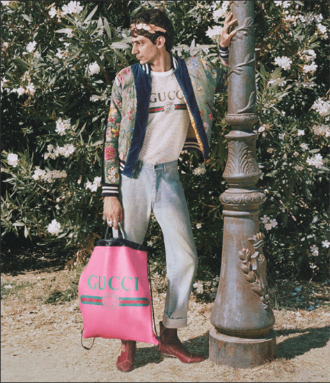 Man wearing headband standing next to pole holding pink gucci bag