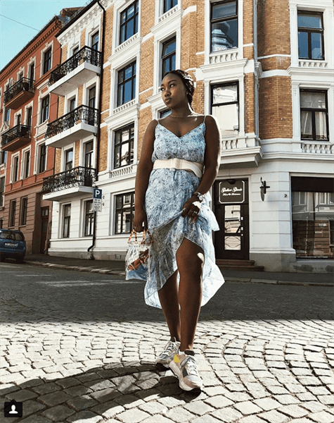Influencer Nnenna Echem wearing spaghetti strap blue floral dress with white belt on street of Norway