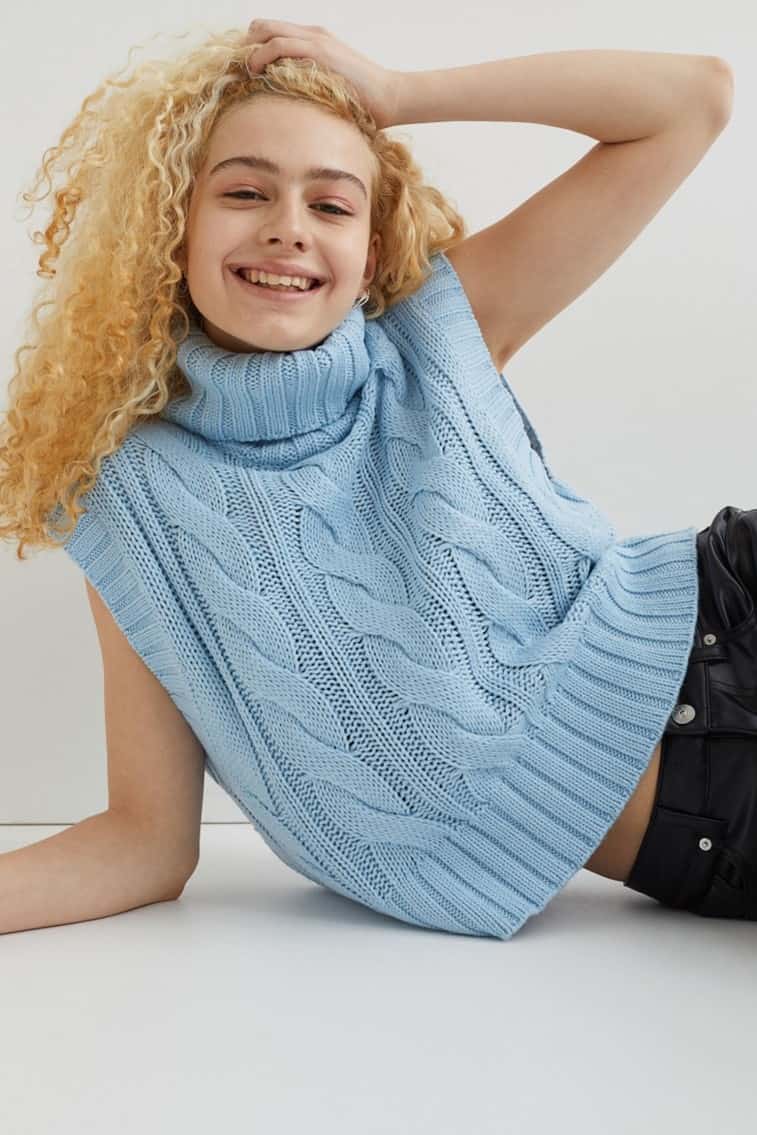Smiling model wearing the sky-blue cable-knit sweater vest from H&M